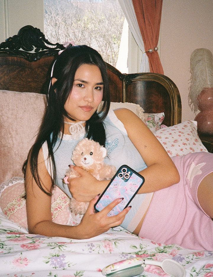 A model poses with a teddy bear and blue and pink kitten Wildflower case