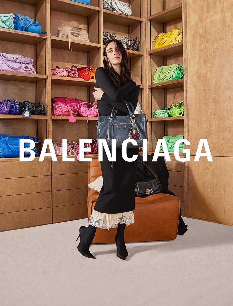 Devon Lee Carlson poses in front of a wall of Balenciaga purses