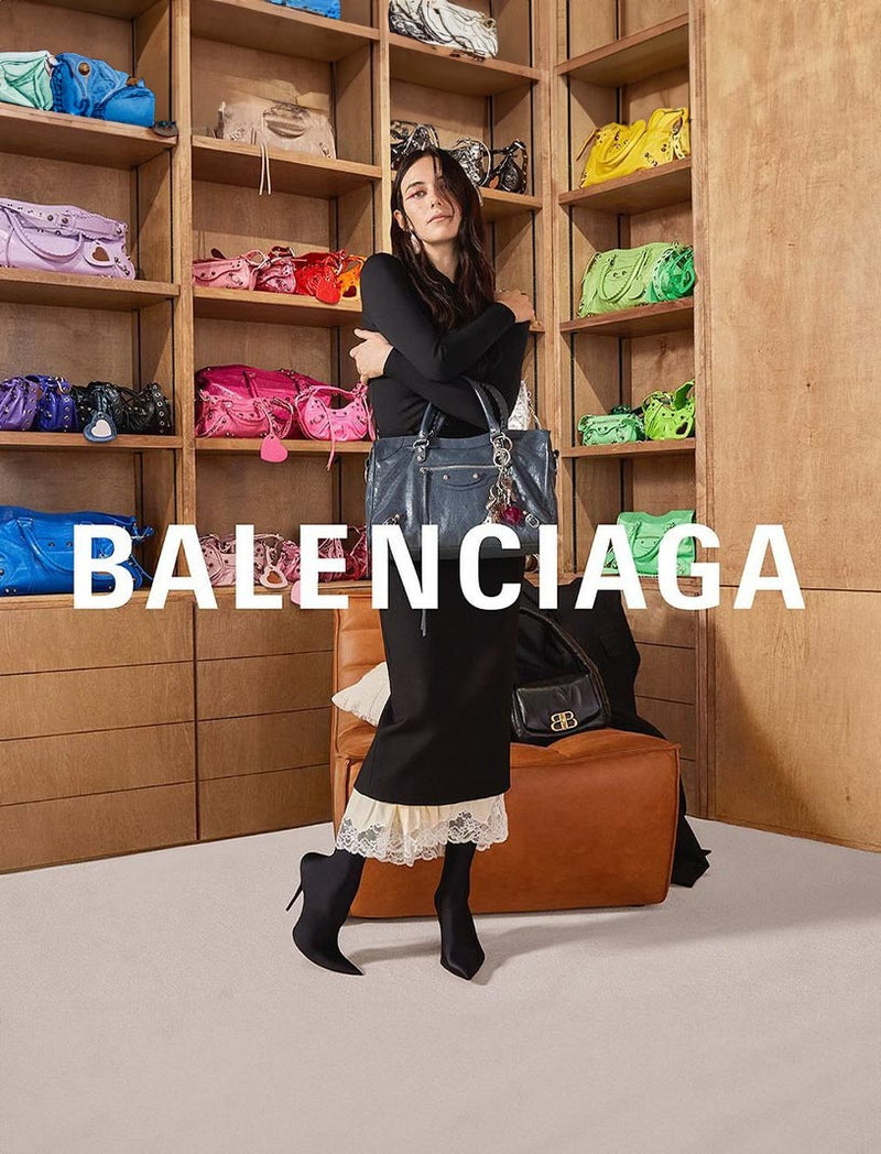 Devon Lee Carlson poses in front of a wall of Balenciaga purses