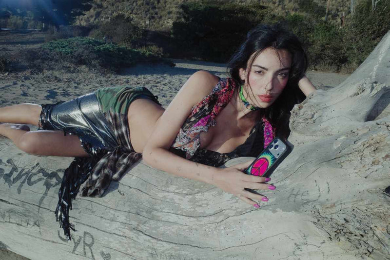 Sav Hudson lays on a fallen tree trunk on a sandy beach