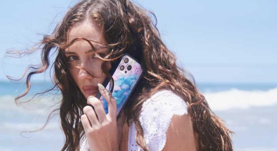 Wildflower iPhone cases arranged with travel accessories. Included are a Union Jack and a black-and-white checkered case, alongside floral and coquette-style cases.