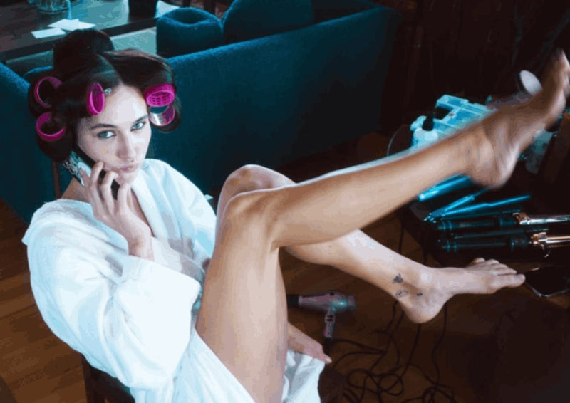 Devon Lee Carlson sits in a robe with pink hair rollers in