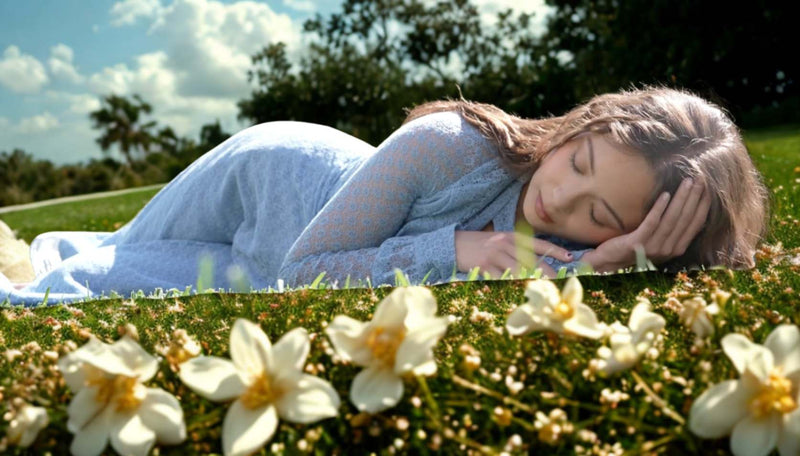 Singer Laufey lays in a field of grass with flowers