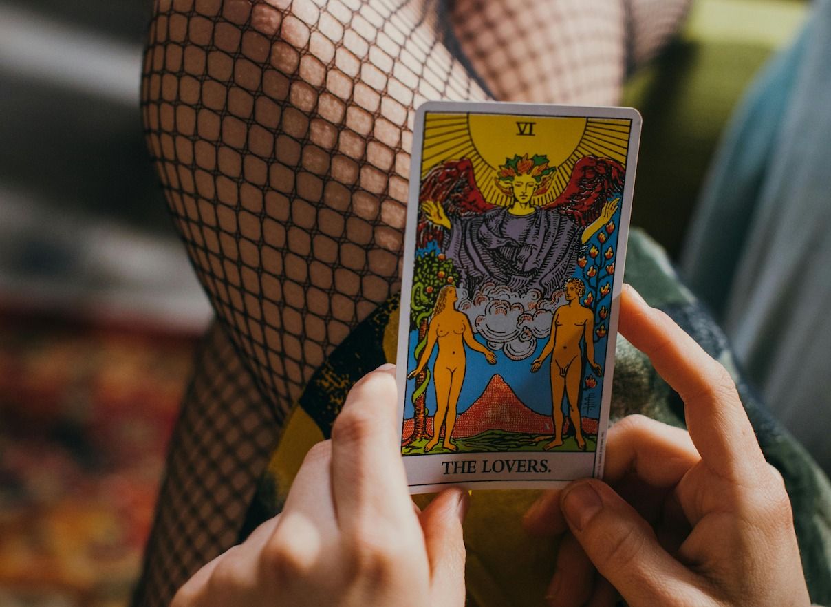 A tarot card is held up that reads 'The Lovers'